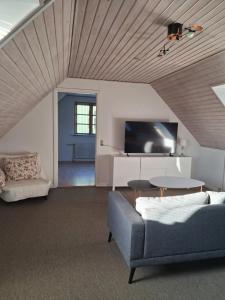 a living room with a couch and a tv at Bakkely in Rønnede