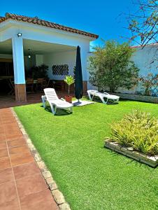 a yard with two lawn chairs and an umbrella at Casa-Chalet Anabel in El Puerto de Santa María