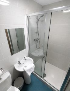 a white bathroom with a shower and a sink at The Saltley Inn in Birmingham