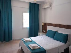 a bedroom with a large bed with blue curtains at Bena pansiyon in Fethiye