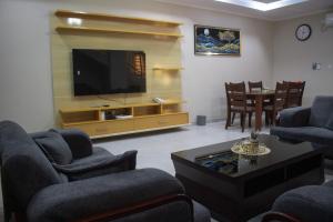 a living room with a tv and chairs and a table at Monga's Apartments in Ndola