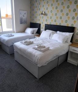 two beds in a hotel room with towels on them at The Saltley Inn in Birmingham
