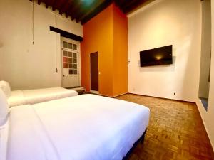 a bedroom with two beds and a flat screen tv at Casa Regina CDMX in Mexico City