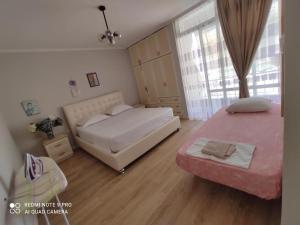a bedroom with two beds and a large window at Himara City-Center Apartment in Himare