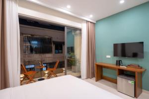 a bedroom with a bed with a television and a balcony at Maison De Hoi An Boutique Homestay in Hoi An