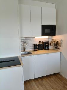 a kitchen with white cabinets and a sink at Gallen-Kallelankatu 9 in Pori