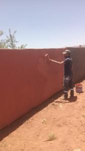 a man leaning against a red wall at Appartement chez bennouri in Telouet