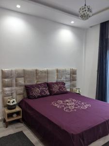 a bedroom with a purple bed with a headboard at MahdiaRafeha in Mahdia