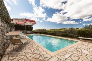 una piscina con sombrilla, mesa y silla en Carlino Vacanze, en Gaiole in Chianti