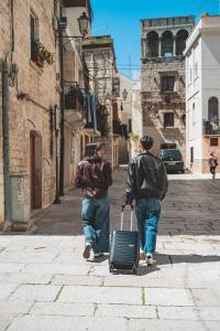 two people walking down a street with a suitcase at Hotel Paradise Rooms in Bitritto