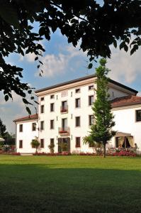 un edificio bianco con un albero di fronte di Hotel Villa Dei Carpini a Oderzo
