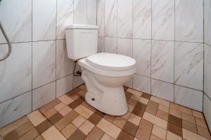 a white toilet in a bathroom with tiled walls at The Cabin Artana By ARBA in Palayangan