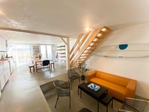a living room with an orange couch and a table at Koala Surf House, en bord d'Océan, planches de surf et skates à disposition in Hossegor