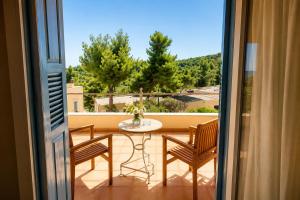 a balcony with a table and chairs and a view at Alonissos Beach Bungalows And Suites Hotel in Alonnisos