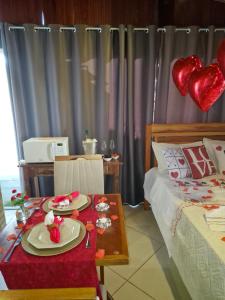a room with a bed and a table with plates and hearts at Luz Residence suíte in Cabo Frio