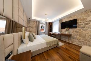 a bedroom with a bed and a stone wall at Hotel Corsaro in Omiš