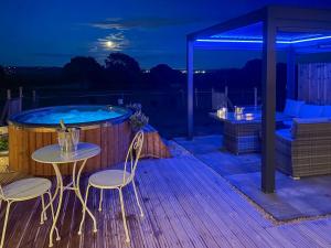 a deck with a hot tub and two chairs and a table at Sky Lark Lodge - Uk49904 in Appley Bridge
