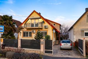 a yellow house with a car parked in front of it at Németh Apartman in Kisapáti