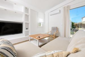 a living room with a couch and a tv and a table at VILLA TOSTi & VILLA JOY in Skala Rachoniou