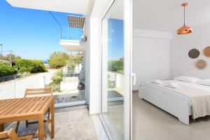 a bedroom with a bed and a table and a balcony at VILLA TOSTi & VILLA JOY in Skala Rachoniou