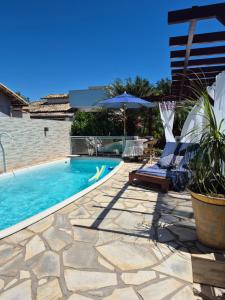 a swimming pool with chairs and an umbrella at Luz Residence suíte in Cabo Frio