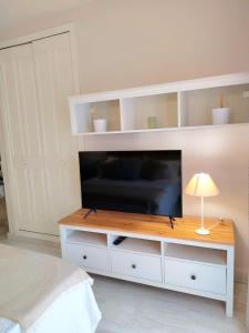 a white entertainment center with a flat screen tv at LolaSuite Confort in El Rocío