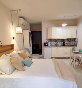 a bedroom with a large white bed and a kitchen at LolaSuite Confort in El Rocío