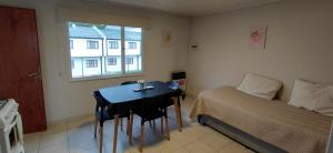 a bedroom with a bed and a table and a window at CALAFATE CENTER APARTS in El Calafate