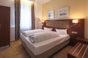 a bedroom with a large bed with white sheets at Hotel Starkenburger Hof in Heppenheim an der Bergstrasse