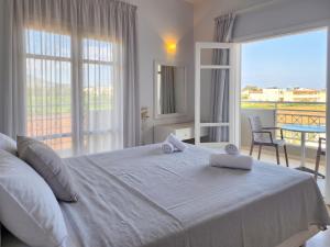 a bedroom with a large white bed and a balcony at Matthew's Place in Malia