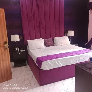 a bedroom with a large bed with a purple headboard at Pointax Apartment Lekki in Ilado +5 photos