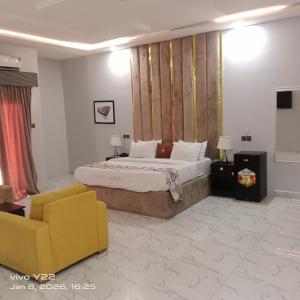 a bedroom with a large bed and a yellow chair at Pointax Apartment Lekki in Ilado