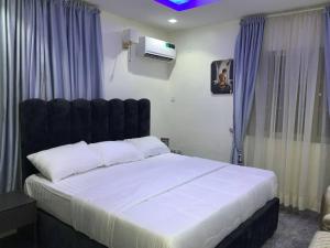 a bedroom with a large white bed with a black headboard at Pointax Apartment Lekki in Ilado