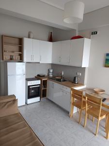 a kitchen with white cabinets and a table with chairs at ANGELA APARTMENT in Koroni