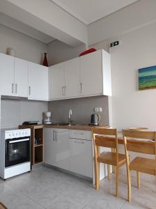 a kitchen with white cabinets and a table and chairs at ANGELA APARTMENT in Koroni