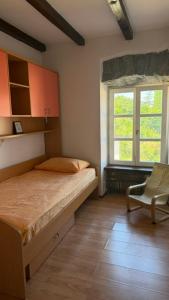 a bedroom with a bed and a chair and a window at Pr' Tekcu in Dekani