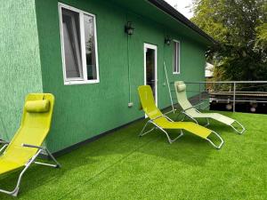 a green house with yellow chairs on the grass at Evergreen Hostel Metrostroevskaya in Almaty