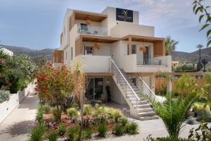 a large white building with a staircase in a garden at Nadia Suites Residencess Adults Only in Malia