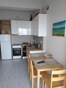 a kitchen with a wooden table and white cabinets at ANGELA APARTMENT in Koroni