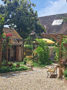 a garden with a bench and an umbrella at Chambre d'hotes de l'Ecu in Preuilly-sur-Claise