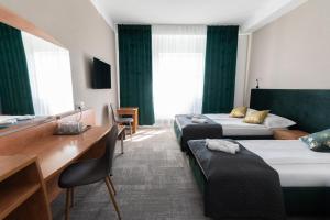 a hotel room with two beds and a desk at Green Hotel in Świebodzin