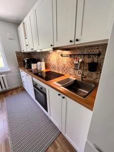 a kitchen with white cabinets and a sink at Leisi Forest View Apartment in Leisi +17 photos