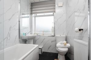 a white bathroom with a tub and a toilet and a sink at Denton Luxury Home - Sleep 8 - Speedy Wi-Fi - Free On-Site Parking in Denton