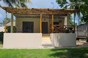 a house with a wooden roof and a white wall at CASA 2 HAB Alberca y Parking privado in Bacalar