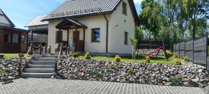 a small house with a rock wall and a playground at Letnisko domek z Sauną i Balią in Lubawka