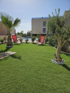 two chairs and trees in a lawn with a building at Apartment Lapis with pool near the beach- by TA Leut Agency in Privlaka