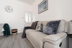 a living room with a couch and a clock on the wall at Denton Luxury Home - Sleep 8 - Speedy Wi-Fi - Free On-Site Parking in Denton +21 photos