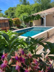 a swimming pool in front of a house with flowers at Petit coin de paradis Périgourdin in Montrem