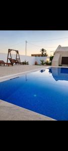 a blue swimming pool with a swing and a table at Dar ennoul in Houmt Souk