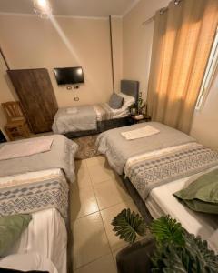 a room with three beds and a tv in it at Pyramids Road Guest House in Cairo